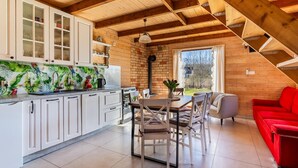 Cucina con mobili bianchi, zona pranzo con tavolo e sedie, e un divano rosso.