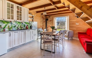 A kitchen with white cabinets, a dining area with a table and chairs, and a red sofa.