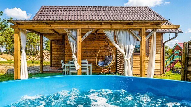 Una baita di legno con piscina, una sedia a dondolo e un'area giochi per bambini.