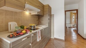 A modern kitchen with a built-in oven, a sink, and a countertop with fresh produce. - Residence La Perla - Apt 39, Monte Isola, Italy (Monte Isola)