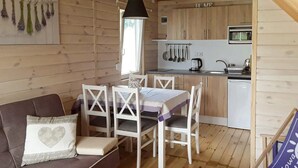 A cozy cabin interior with a dining area, a sofa with cushions, a kitchen with wooden cabinets, and a hanging light fixture. - 2 bedroom lovely home in Gaski (Gaski)