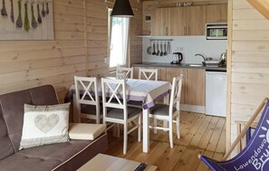 A cozy cabin interior with a dining area, a sofa with cushions, a kitchen with wooden cabinets, and a hanging light fixture. - 2 bedroom lovely home in Gaski (Gaski)