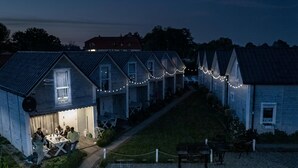 A row of wooden houses with string lights, a gravel path, and a grassy hill. - 2 bedroom lovely home in Gaski (Gaski)