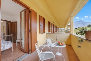 A balcony with a table set for two, a bed, and a view of the landscape. - Residence La Perla - Apt 40, Monte Isola, Italy (Monte Isola)