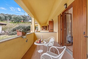 Ein Balkon mit Tisch für zwei Personen, einer Weinflasche und einer Obstplatte.