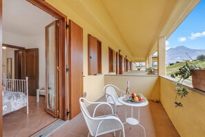 A balcony with a table set for two, a bed, and a view of the landscape. - Residence La Perla - Apt 41, Monte Isola, Italy (Monte Isola)