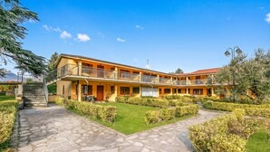 A two-story building with a stone-paved entrance and a well-maintained garden. - Residence La Perla - Apt 41, Monte Isola, Italy (Monte Isola)
