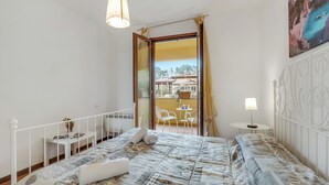 A bedroom with a bed, a bedside table, a lamp, and a view of a balcony with outdoor furniture. - Residence La Perla - Apt 41, Monte Isola, Italy (Monte Isola)