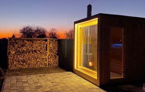 Uma cabana de madeira com estrutura de vidro, parede de pedra e piso de tijolos.