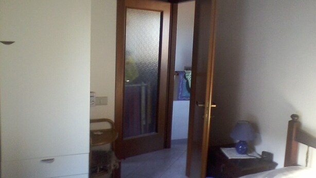 A bedroom with a bed, a nightstand, a dresser, and a door leading to a balcony. - Cibo 17 - Two-room apartment with sea view (Capraia Isola)
