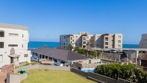 Zona residencial costera con edificios modernos, cielo despejado y vistas al mar.