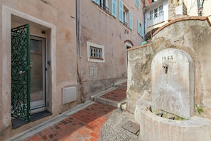 A narrow alleyway with a door, a small window, and a stone wall with a plaque. - House Old Town 50m Beach and Shop, Menton, France (Menton)