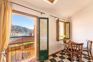 A balcony with a view of a coastal town and mountains, a checkered floor, and a table with chairs and a vase of flowers. - House Old Town 50m Beach and Shop, Menton, France (Menton)