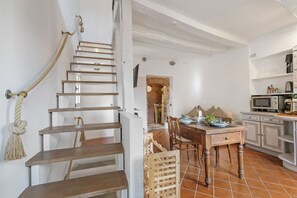 A staircase with a rope, a dining area with a table and chairs, and a kitchen area with cabinets and appliances. - House Old Town 50m Beach and Shop, Menton, France (Menton)