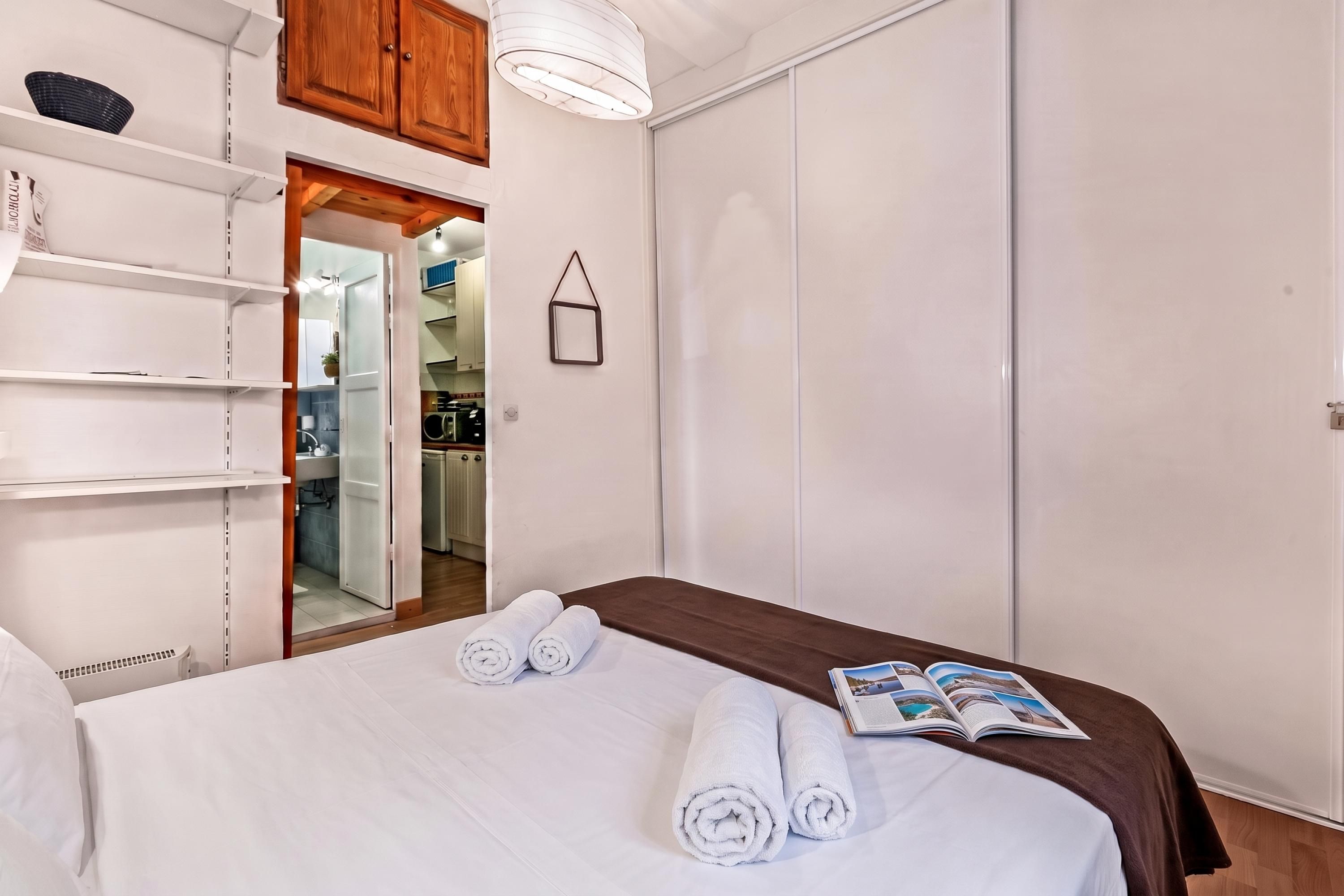 Ein Hotelzimmer mit einem Bett, einem Kleiderschrank, einer Regaleinrichtung und einer Tür zu einem Badezimmer.