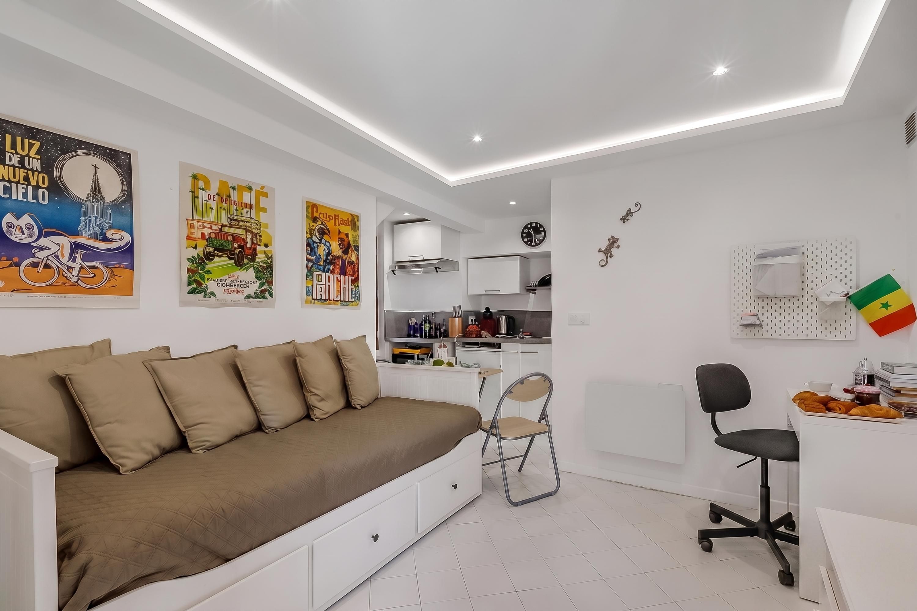 A modern room with a sofa, a dining area, and kitchenettes.
