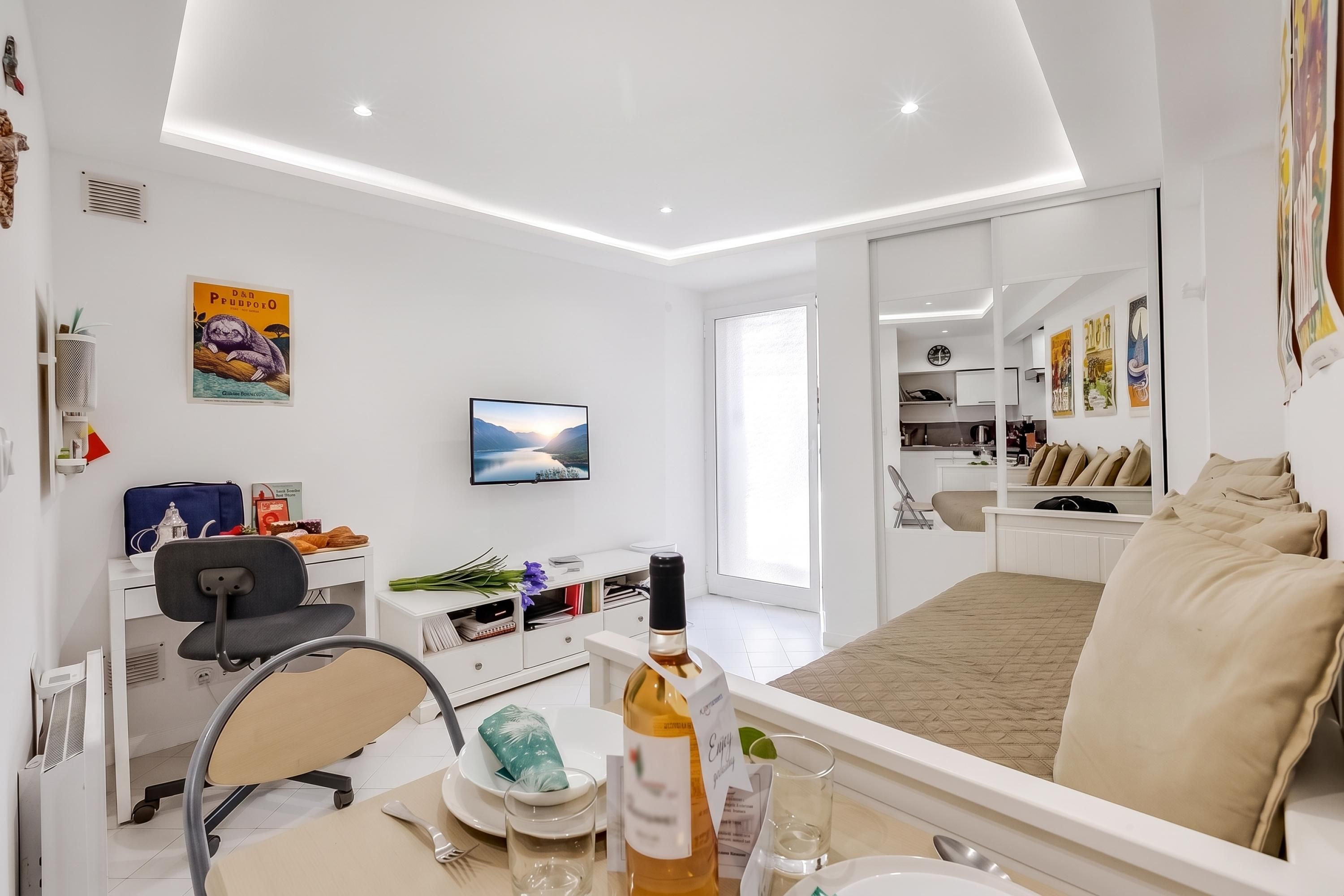 A modern hotel room with a bed, desk, chair, and a TV on the wall.