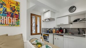 Una cocina moderna con armarios blancos, una mesa de comedor y una obra de arte colorida en la pared.