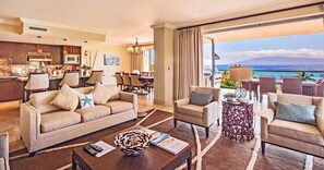 Ein Hotelzimmer mit Wohnbereich, Essbereich und einem Balkon mit Meerblick.