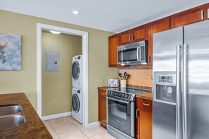 A compact kitchen with a washing machine, microwave, oven, and refrigerator. - NEW! KBM Resorts | 3 FREE CARS | Honua Kai Konea | Ocean View Resort | Spacious 8-Bedroom Multi-Unit Listing! HK ML-3383 (Lahaina)