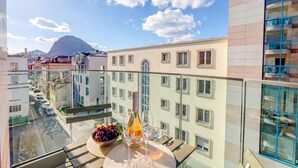 Un balcon avec une bouteille de vin, des verres et un saladier de fruits.