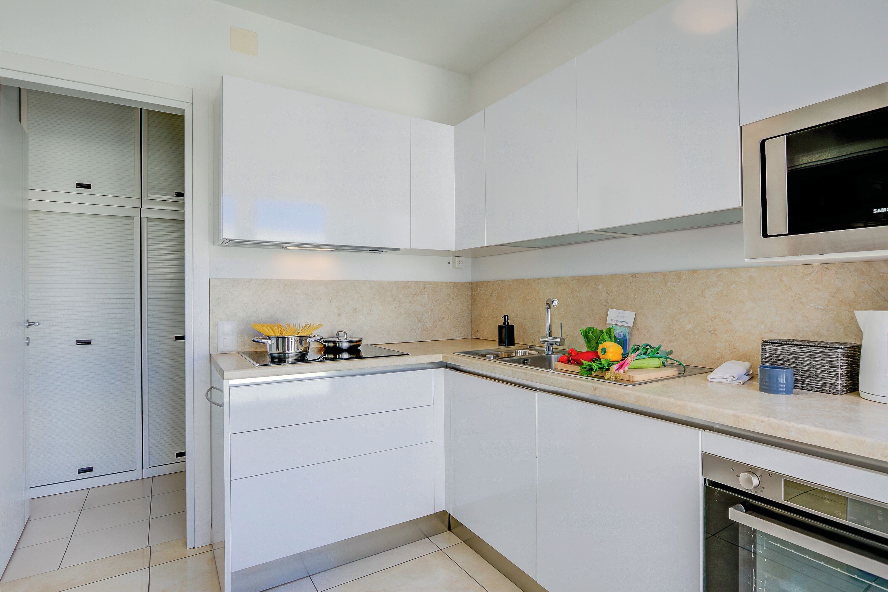 A modern kitchen with white cabinetry, a stainless steel sink, and a built-in oven.