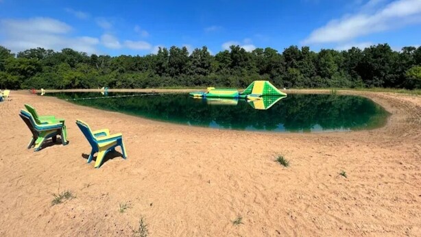 Une plage de sable, une piscine et des chaises longues vertes et jaunes.