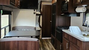 Une cuisine compacte pour camping-car, avec des placards en bois, un four à micro-ondes, une cuisinière et un évier.
