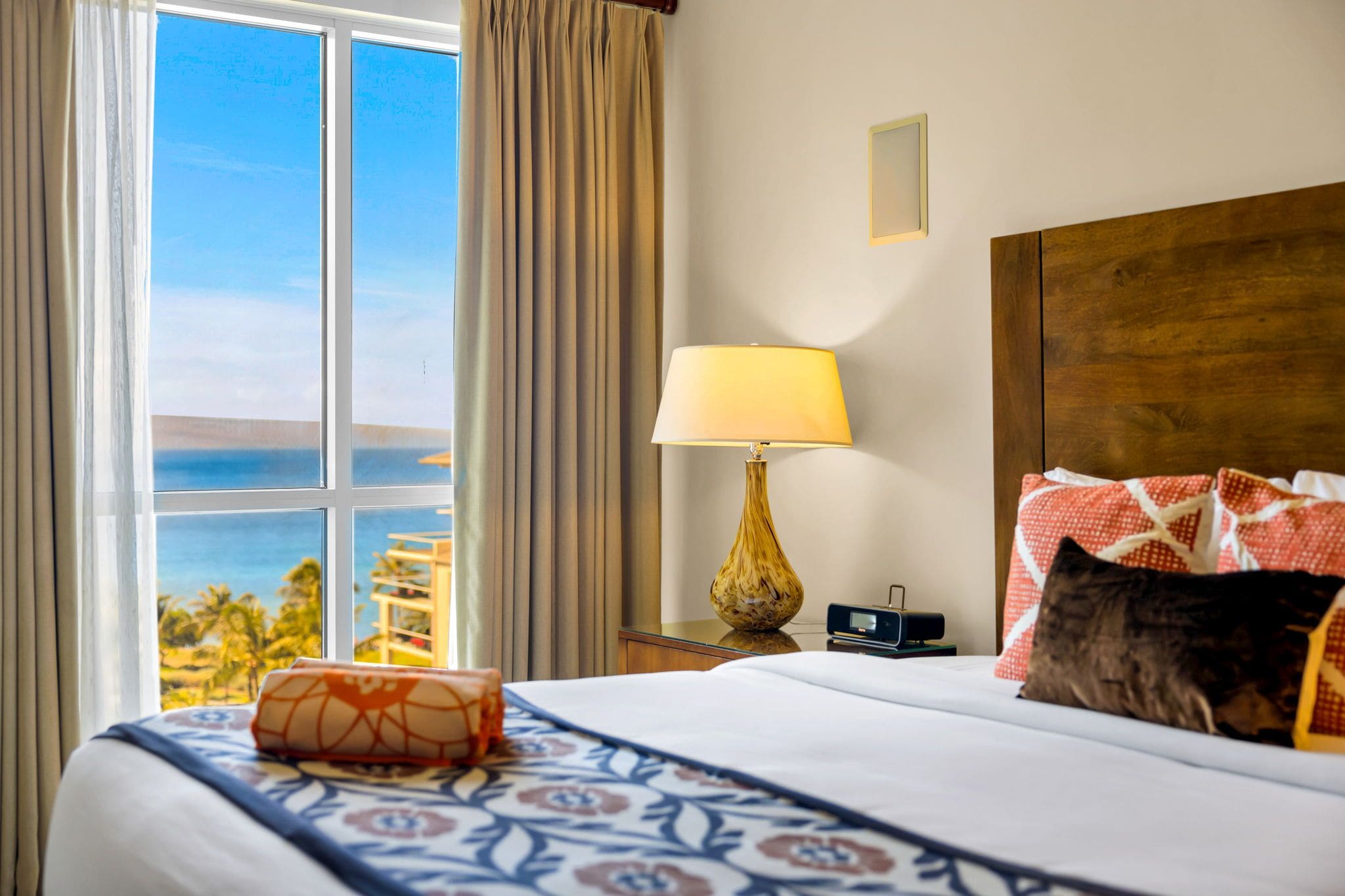 Une chambre d’hôtel avec un lit, une lampe, une table de chevet et une vue sur l’océan.