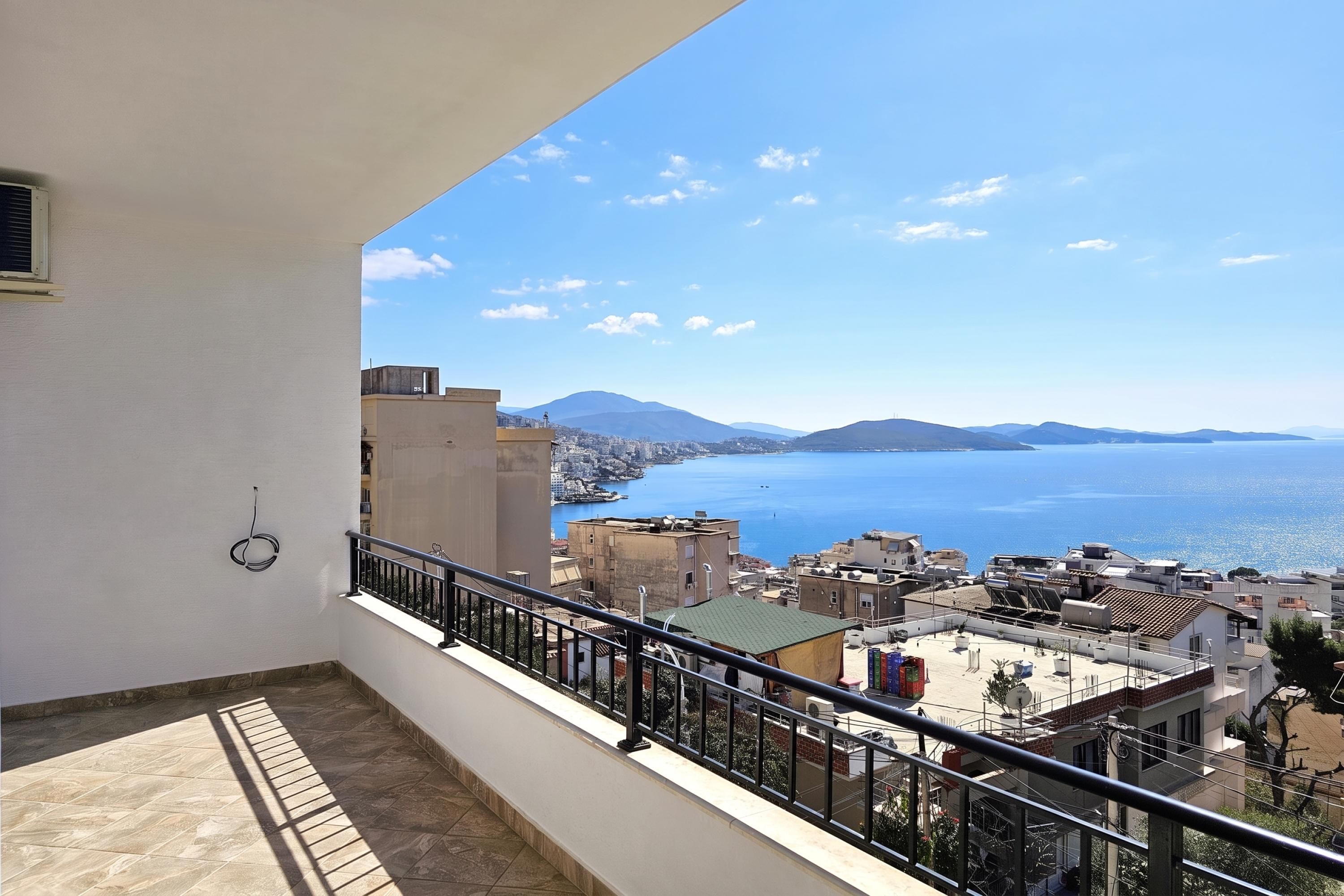 A balcony with a view of a coastal cityscape and a large body of water.