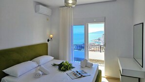 Una habitación de hotel con cama, ventana con vistas, ventilador de techo y aire acondicionado de pared.