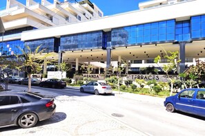 Un edificio moderno con fachada de vidrio, un acceso cubierto y un cartel que dice 'SANDAN TERRACES'.