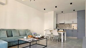 Een moderne woonkamer met een bank, salontafel en een eethoek met stoelen en een tafel.
