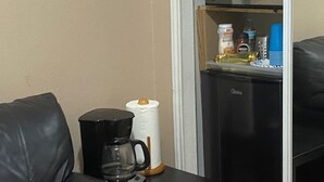 Een kitchenette met een koffiezetapparaat, een rol keukenpapier en een magnetron.