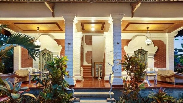 A building with a covered entrance, columns, and steps leading to a door.
