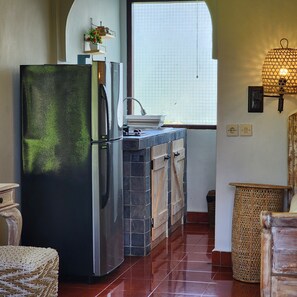 A kitchen with a refrigerator, a sink, and a window with blinds. - Danaya Cottage Ubud (Ubud)