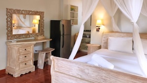 A bedroom with a canopy bed, a wooden dresser, a mirror, a refrigerator, and a clock on the wall.