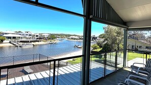 Ein Balkon mit Blick auf einen Fluss, einen Steg und Häuser am gegenüberliegenden Ufer.