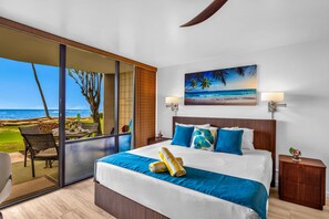 Een slaapkamer met een groot bed, uitzicht op zee, een balkon met buitenmeubilair en een schilderij van een strand.