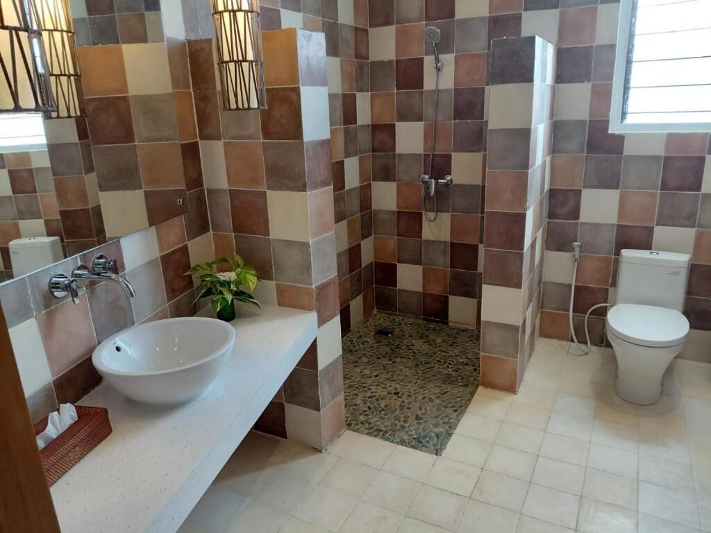 A bathroom with a white sink, a shower, and a toilet.