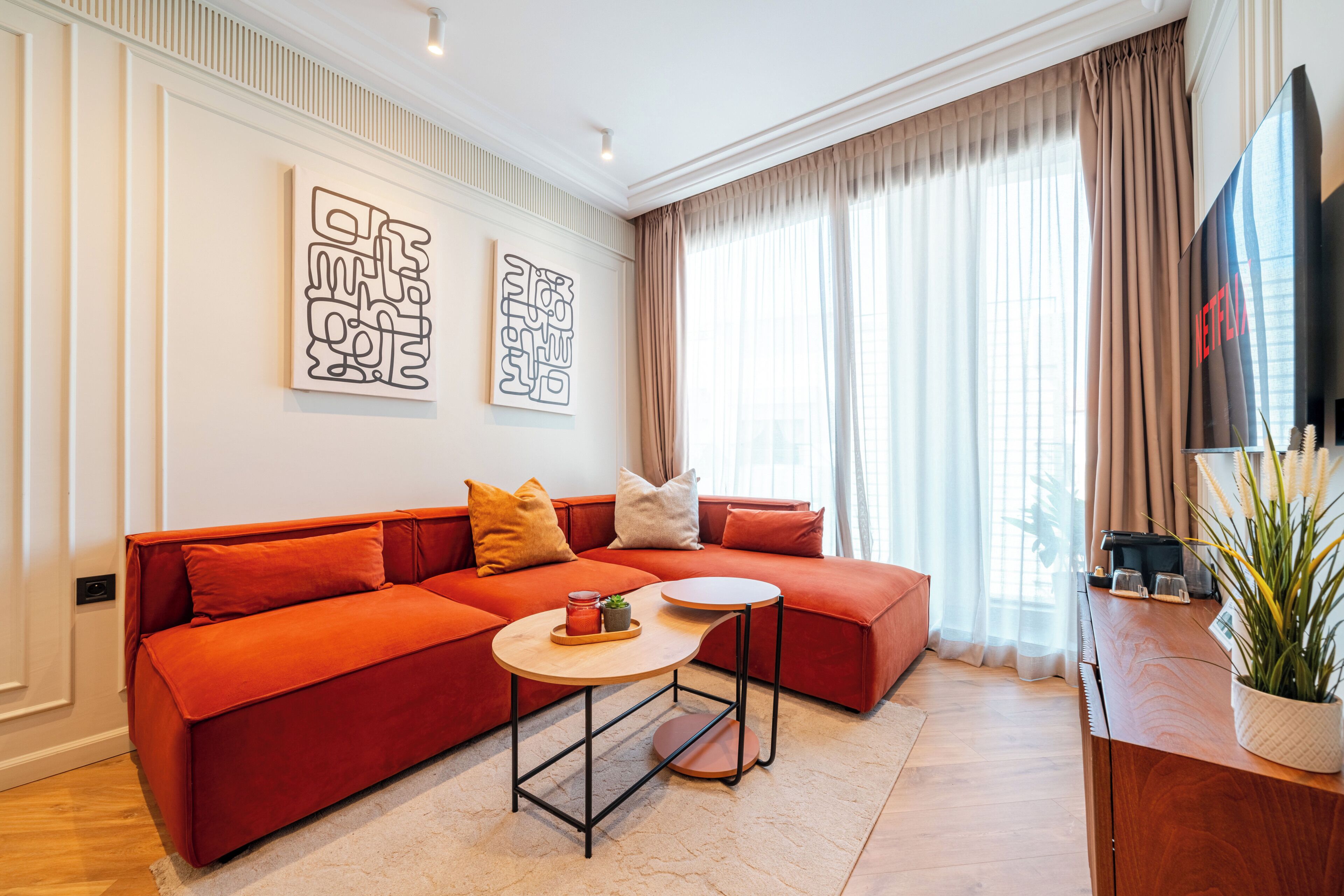 A modern living room with a red sofa, a round coffee table, and a flat-screen TV.