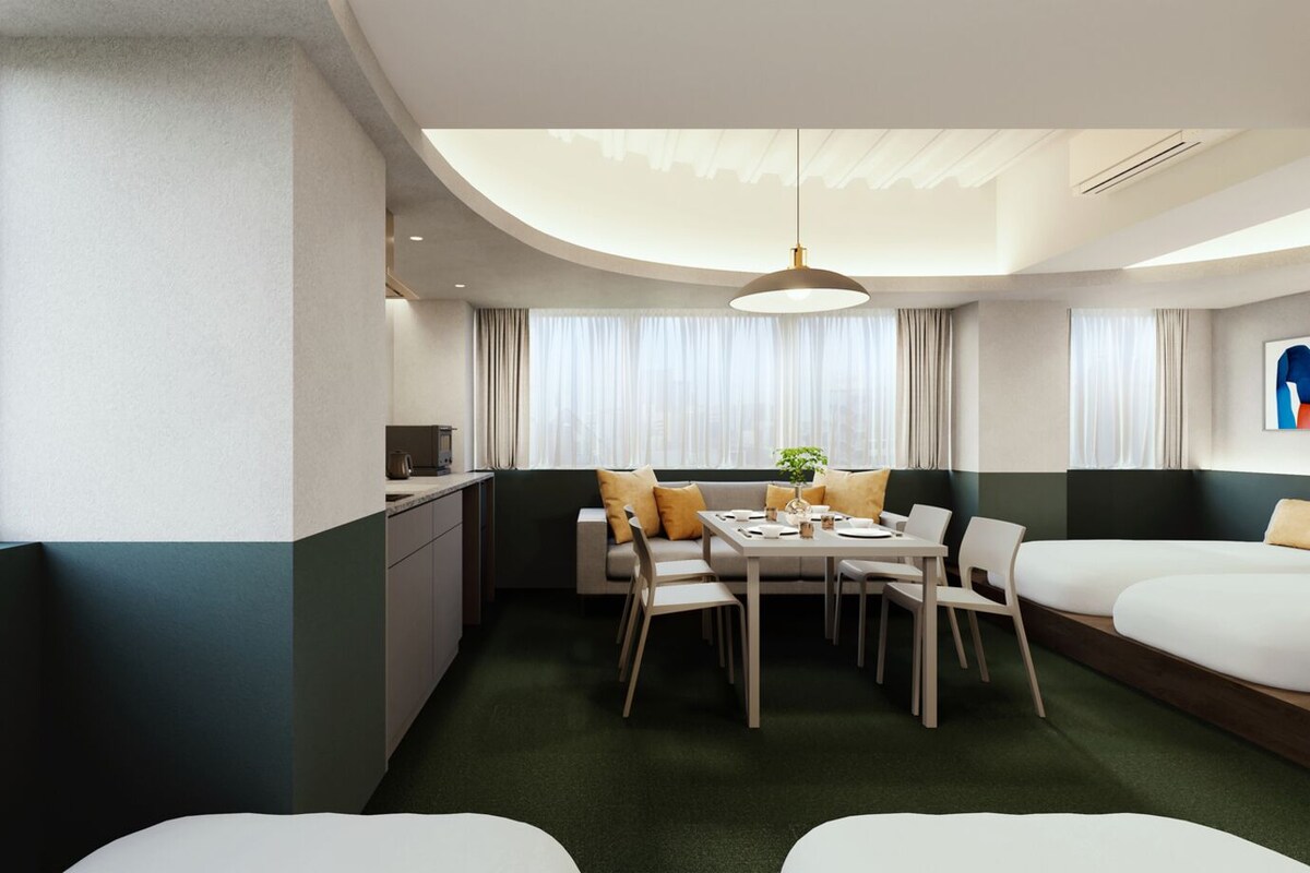A modern hotel room with a dining area, a sofa, a bed, and a view of the city.