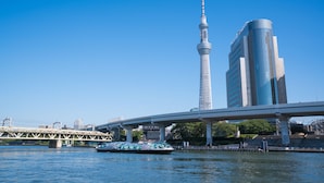 A river with a boat, a bridge, and two tall buildings. - HUBEX AKIHABARA (Tokyo)