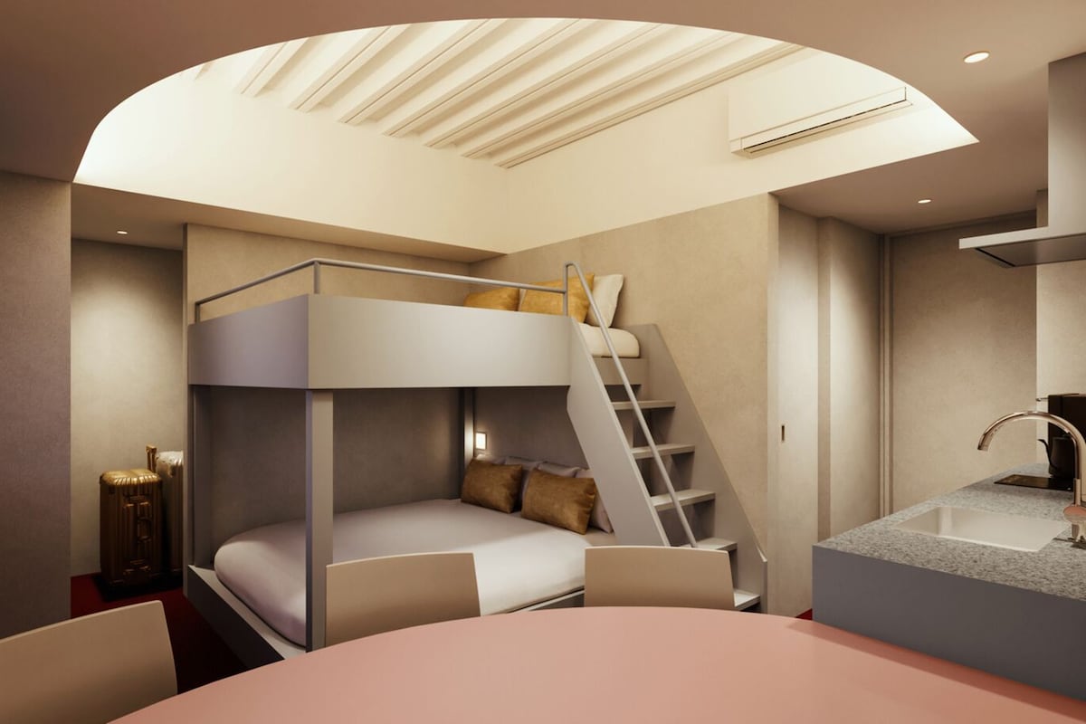 A bunk bed with a desk and chair, a staircase, a sink, and a ceiling light fixture.