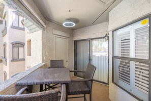 A balcony with a table and chairs, a door, and a window with blinds. - Spacious 2BR 2BA Condo Getaway for 6 (Scottsdale)