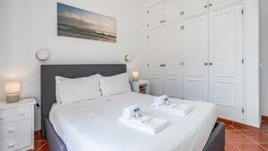 Una habitación de hotel ordenada con cama, mesita de noche, un cuadro colgado en la pared y un armario.