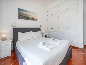 Ein ordentlich eingerichtetes Hotelzimmer mit einem Bett, einem Nachttisch, einem Wandbild und einem Kleiderschrank.