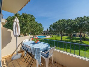 A balcony with a table, chairs, and a pool in the background. - Pool retreat at Clube da Bemposta (Alvor)