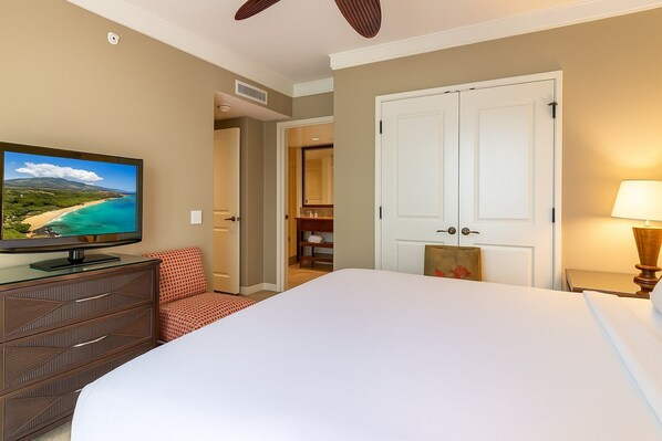 A hotel room with a bed, a television, a desk with drawers, a chair, a door, and a nightstand with a lamp. - 2 Honua Kai Villas | Mountain View | Sleeps 10 | Free Car w/ 6+ Nights | ML-3827 (Lahaina)