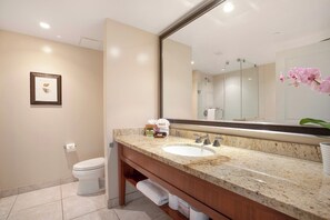 Un baño con lavamanos de mármol, un espejo grande, un inodoro y un cuadro en la pared.